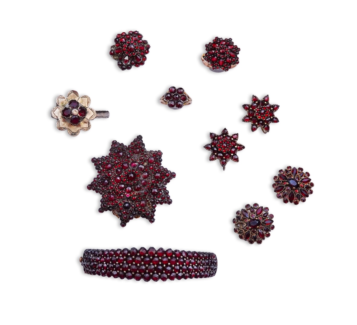 A suite of garnet and paste jewellery, comprising: a brooch, 5cm diameter; a bangle, inner circumference 16cm; two rings, sizes I and M; a pair of earrings, and a single earring, each set with rose-cut garnets; and a pai